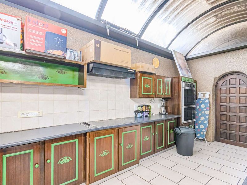 A dated kitchen featuring built-in cabinetry, a built-in oven, and a unique arched wooden door under a translucent barrel vault roof.