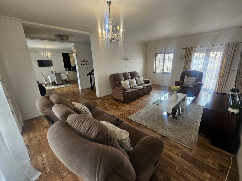 Spacious open-plan living area featuring laminate flooring, elegant chandelier lighting, and direct access to the exterior through French doors.