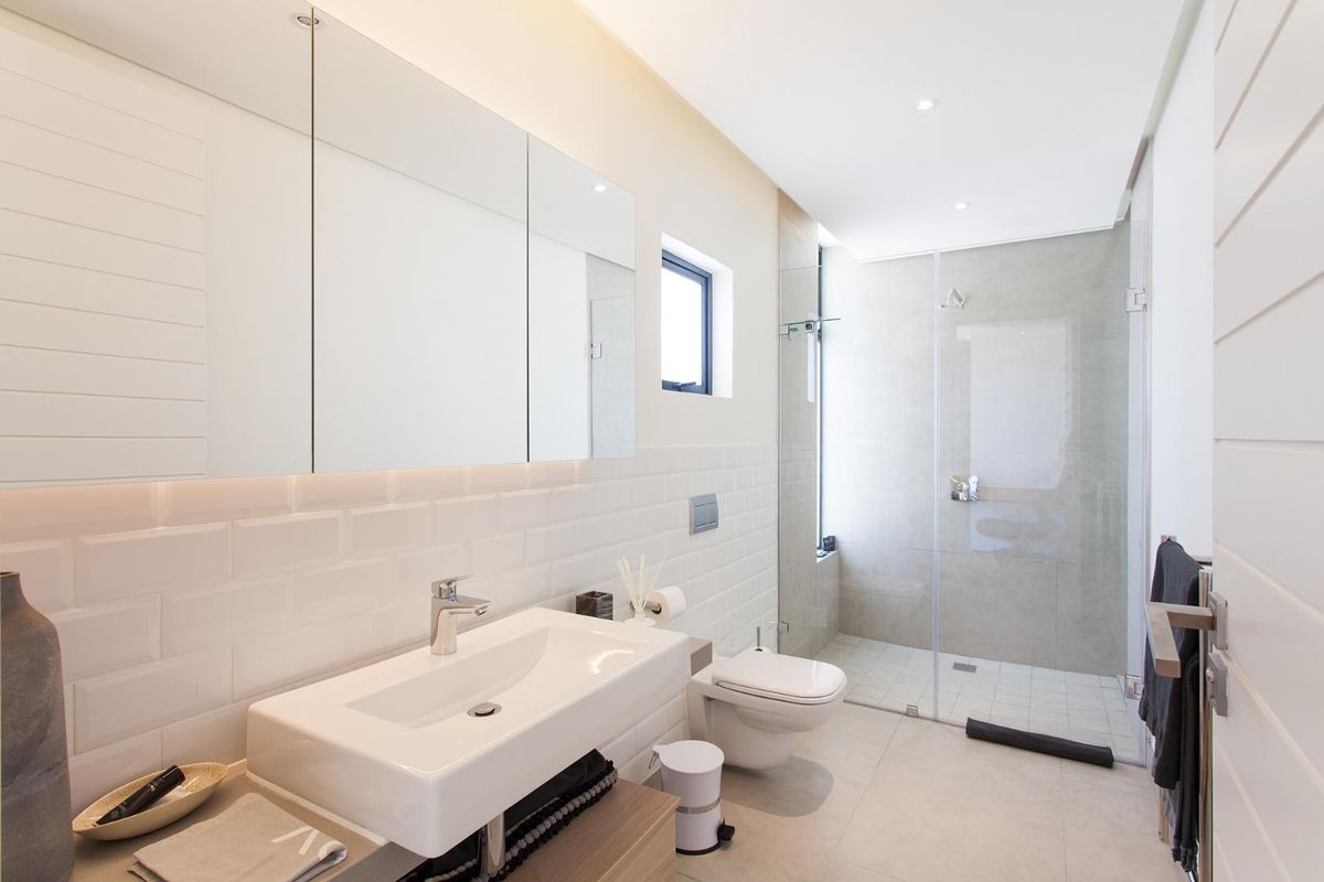 Modern bathroom featuring a wall-mounted vanity with integrated basin, subway tile backsplash, wall-hung toilet, and a spacious walk-in shower with glass screen.