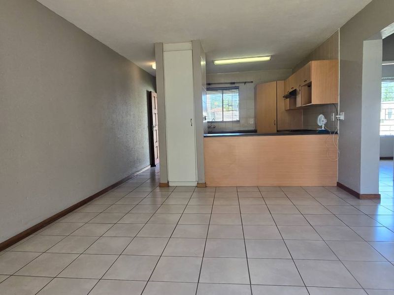 Open plan living and kitchen area featuring tiled flooring, built-in cabinetry, and a breakfast counter, offering a functional and versatile layout.