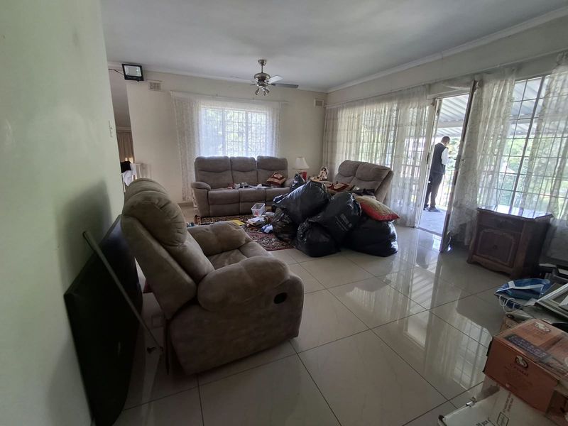 Spacious living room featuring large format floor tiles, a ceiling fan, and direct access to an outdoor patio area through sliding glass doors.