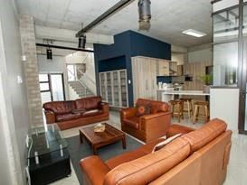 Spacious open-plan office area featuring an industrial aesthetic with exposed concrete ceilings, modern built-in cabinetry, and a glass-partitioned meeting space.