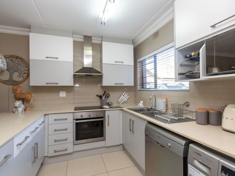 Modern kitchen featuring sleek cabinetry, stone countertops, integrated appliances, and a tiled backsplash, offering a functional and well-maintained cooking space.