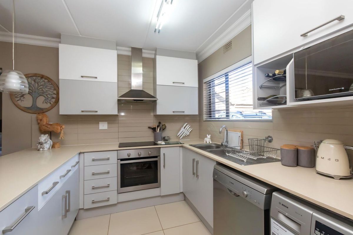 Modern kitchen featuring sleek cabinetry, stone countertops, integrated appliances, and a tiled backsplash, offering a functional and well-maintained cooking space.