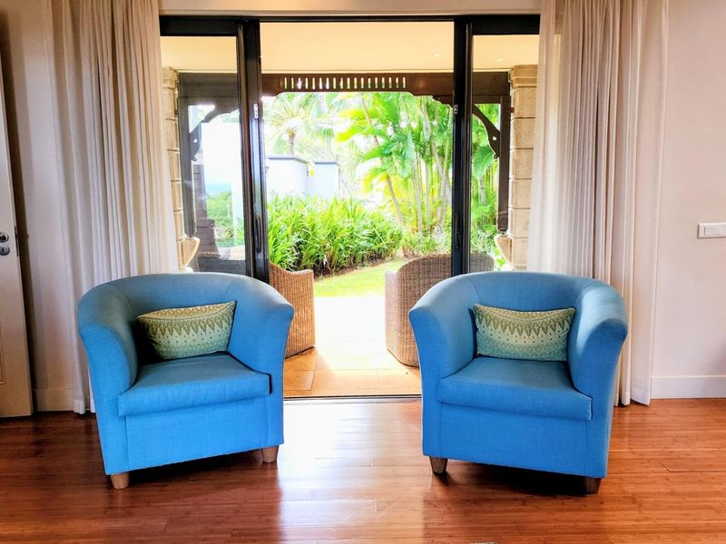 A bright living area featuring polished hardwood floors and large sliding glass doors that provide seamless access to the outdoor patio and garden.