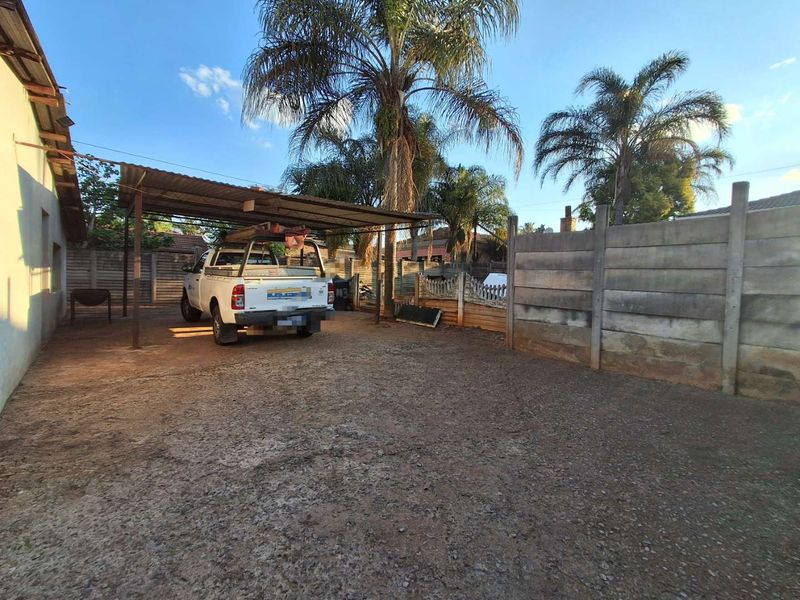 Outdoor carport area with a gravel driveway and precast concrete boundary walling.