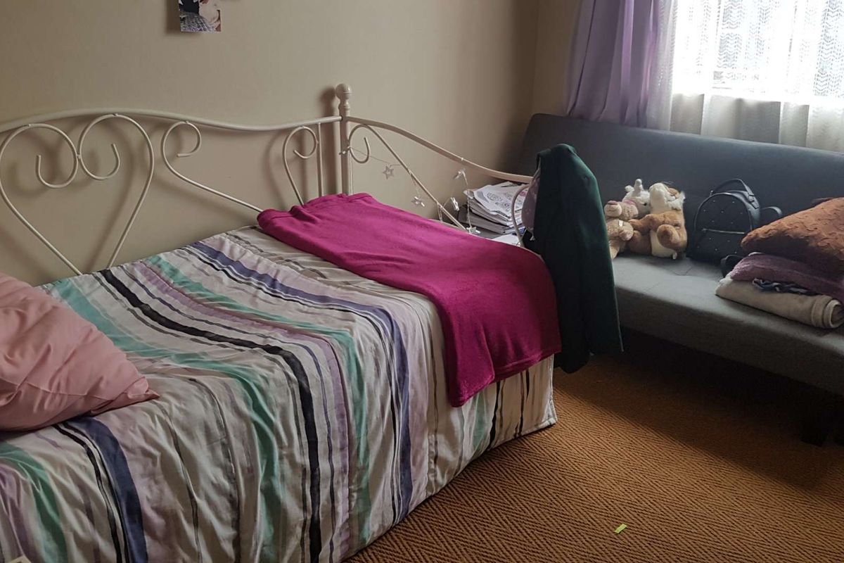 A bedroom featuring carpeted flooring and a window with curtains, providing a functional living space.