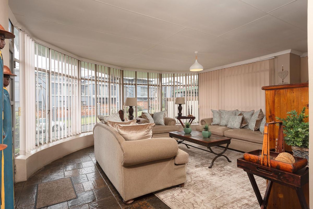A spacious living room featuring large curved windows that provide ample natural light and a view of the exterior.