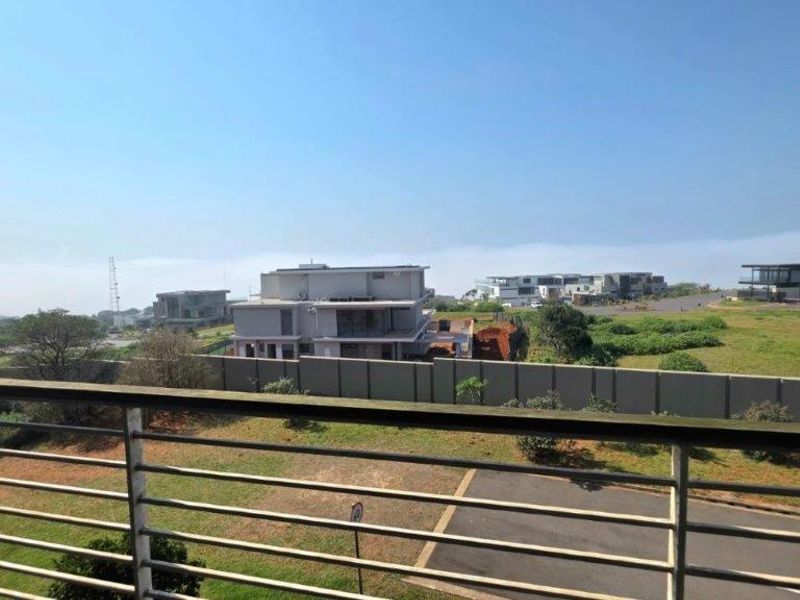 An elevated view overlooking a residential estate with a clear horizon and a metal balustrade in the foreground.
