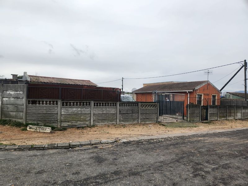 Front view of a residential property featuring a precast concrete boundary wall, metal security gate, and a tiled roof structure.