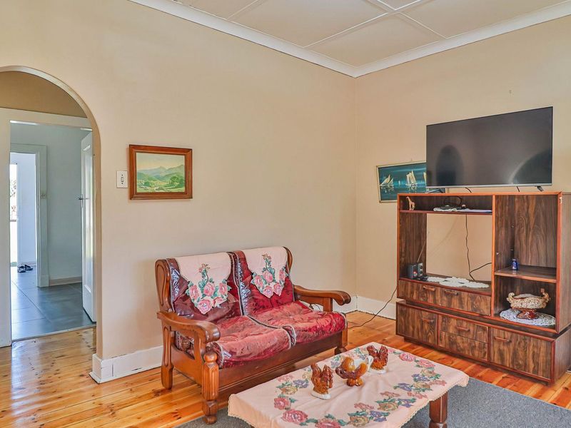 A living room featuring timber flooring, an arched doorway leading to an adjacent space, and a tiled ceiling.