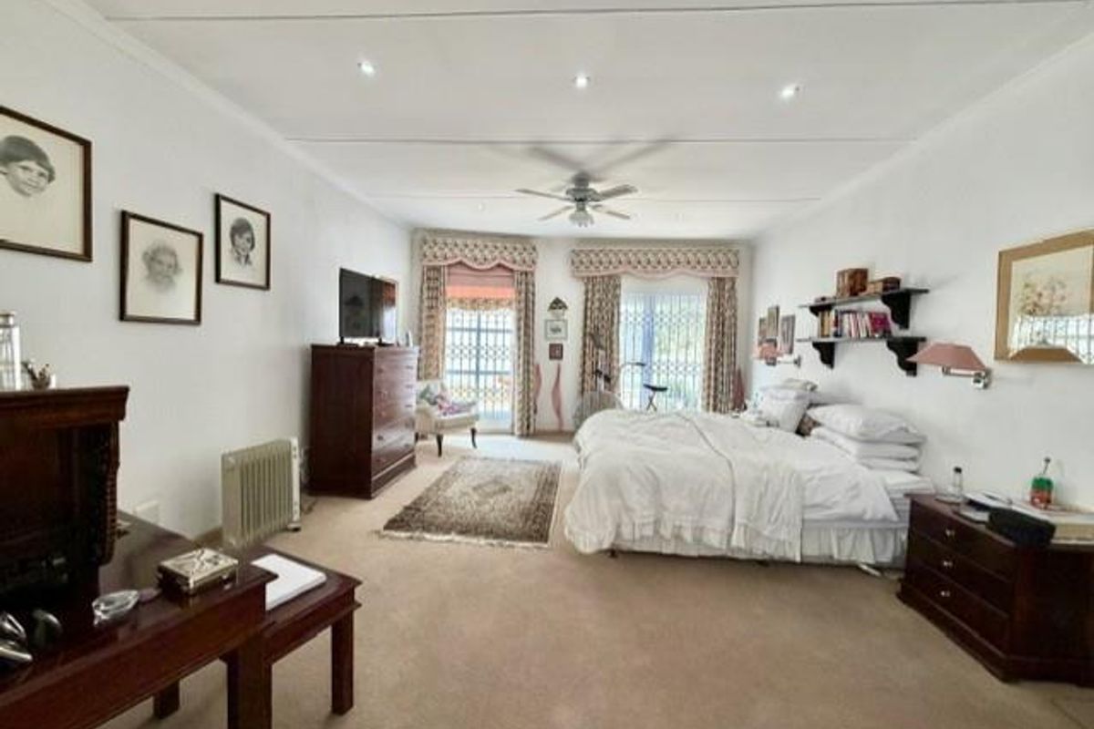 Spacious bedroom featuring neutral carpeting, recessed lighting, a ceiling fan, and sliding glass doors with security gates leading to an outdoor area.