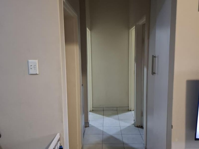A functional hallway with neutral wall finishes and tiled flooring, providing access to multiple rooms within the apartment.