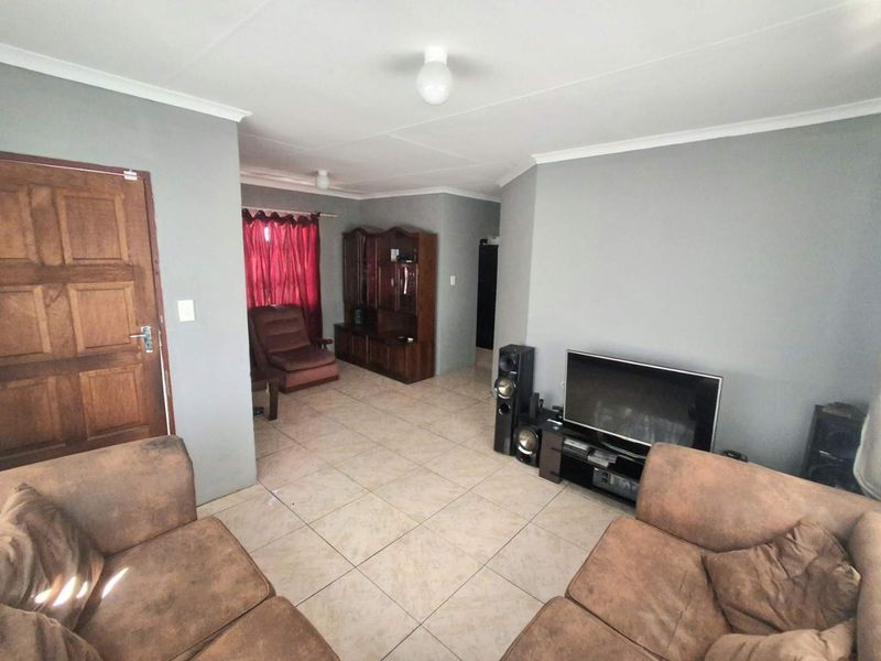 A living room featuring neutral grey walls, tiled flooring, and a coved ceiling, providing a functional and well-lit space.