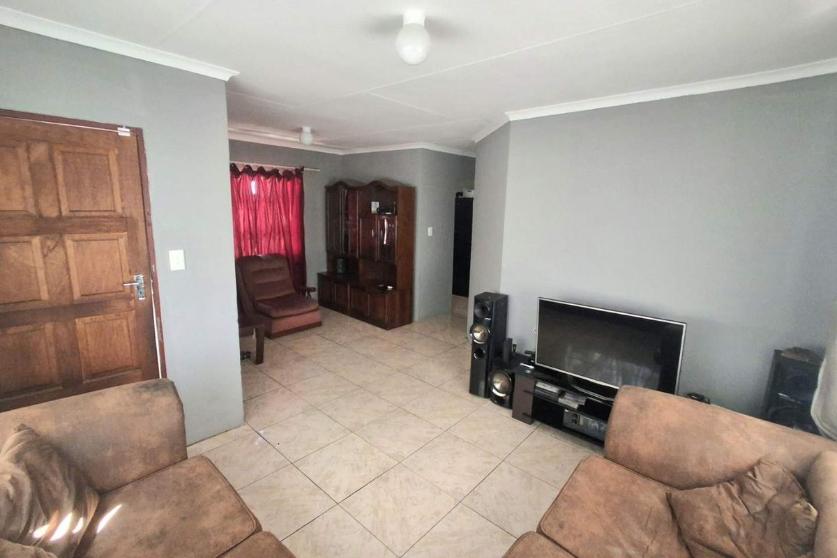 A living room featuring neutral grey walls, tiled flooring, and a coved ceiling, providing a functional and well-lit space.