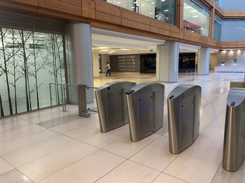 Modern office building lobby featuring secure access turnstiles, polished tiled flooring, and contemporary architectural finishes.