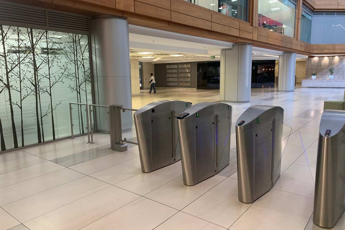 Modern office building lobby featuring secure access turnstiles, polished tiled flooring, and contemporary architectural finishes.