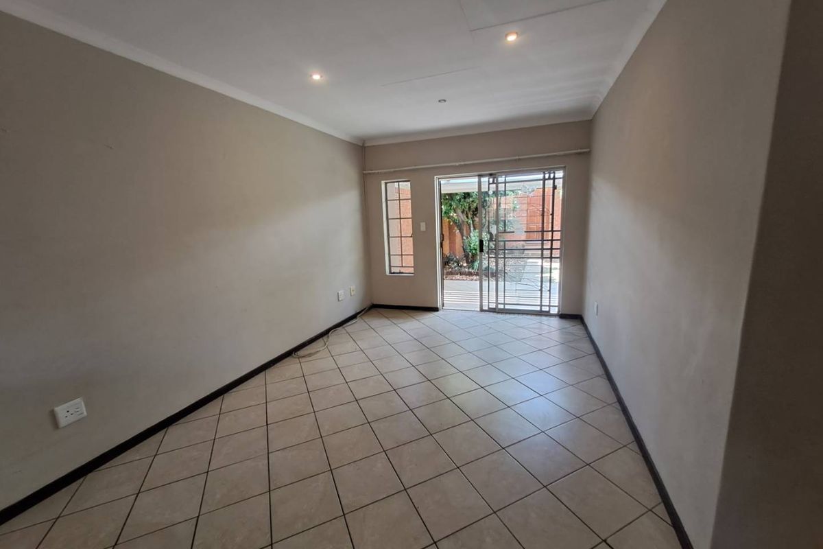 An empty living room featuring tiled flooring, recessed lighting, and a sliding glass door providing access to the outdoor area.