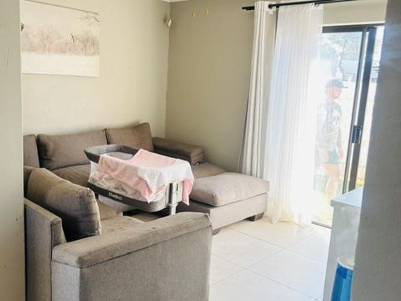 A living room featuring tiled flooring, a ceiling fan, and a sliding glass door providing access to the exterior.