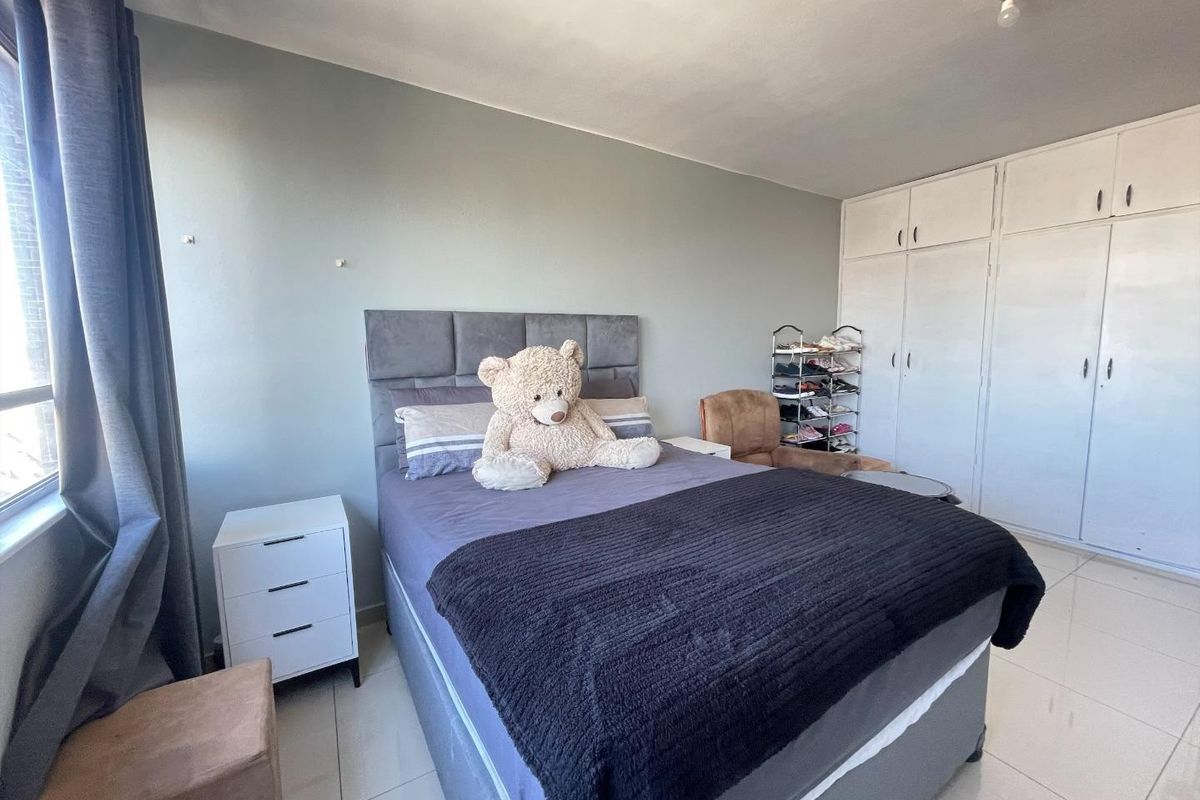 A bedroom featuring tiled flooring and ample built-in cupboard storage space.