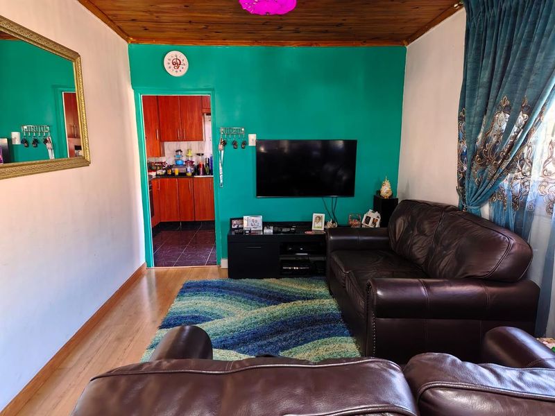 A living room featuring laminate flooring and a timber ceiling, with a direct view into the adjacent kitchen area.