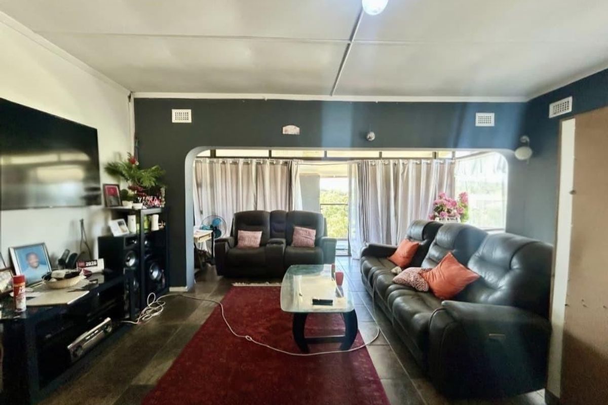 A living room featuring tiled floors, an arched transition to an adjacent space, and sliding glass doors leading to an outdoor area.