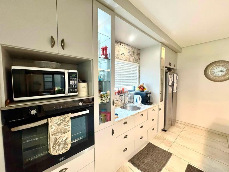 A well-maintained kitchen featuring built-in oven and microwave, granite countertops, undermount sink, and ample cabinetry with glass display sections.