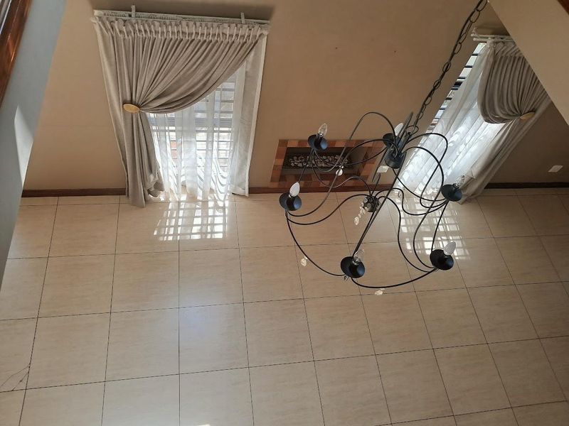 Spacious living area featuring large format floor tiles, a built-in fireplace, and a decorative chandelier, viewed from an elevated perspective.