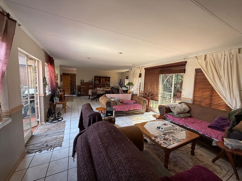 Spacious open-plan living and dining area featuring tiled flooring, large sliding glass doors providing natural light, and direct access to the outdoor patio.