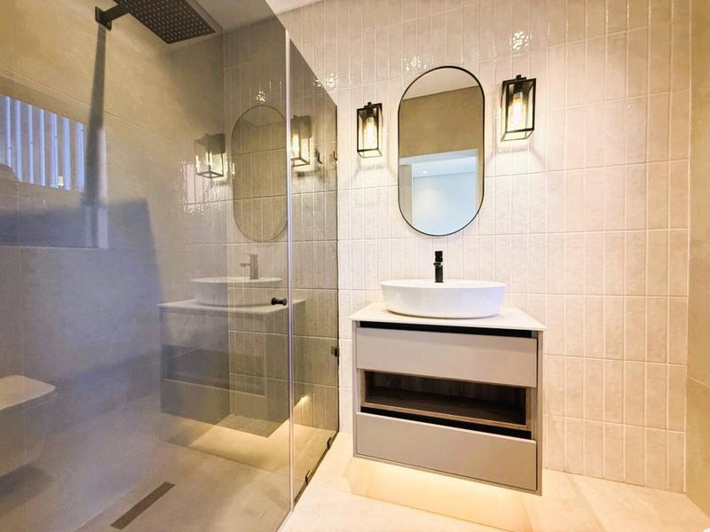 Modern bathroom featuring a floating vanity with vessel sink, walk-in shower with glass screen, and contemporary wall sconces.