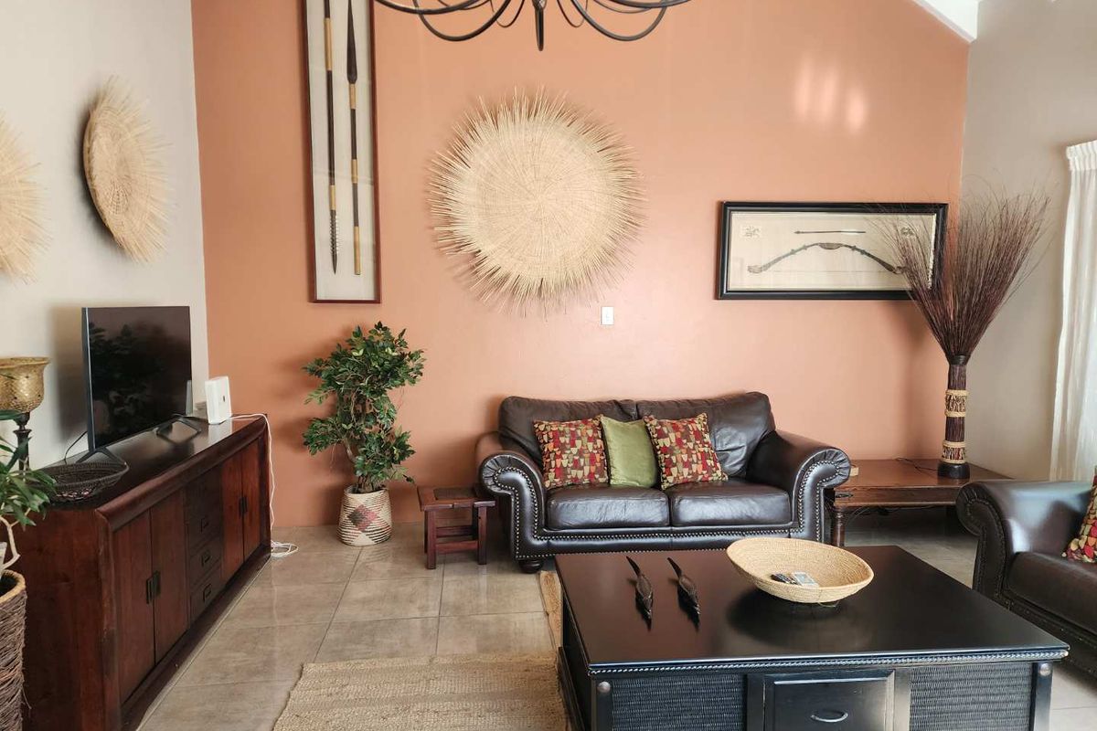 Spacious living room featuring high vaulted ceilings, tiled flooring, and a prominent feature wall.