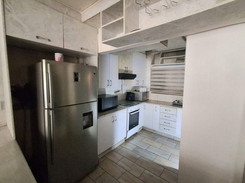 A functional kitchen featuring built-in cabinetry, an integrated oven and hob, extractor fan, and tiled flooring.
