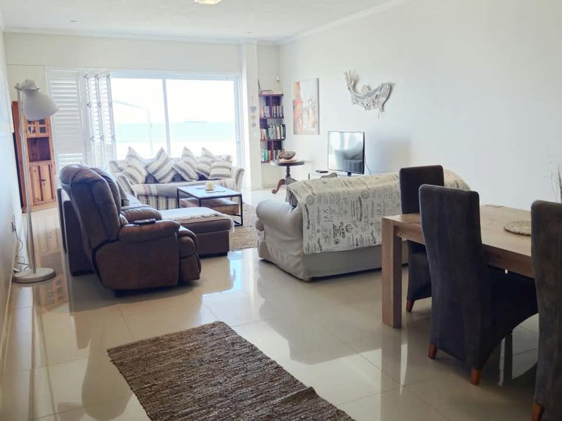 Spacious open-plan living and dining area featuring polished tiled flooring, recessed lighting, and large sliding glass doors leading to an outdoor space.