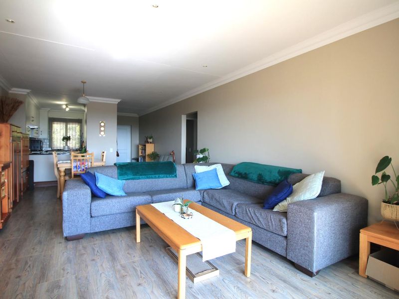 Spacious open-plan living and dining area featuring modern laminate flooring, neutral wall tones, and a functional kitchen layout with integrated cabinetry.