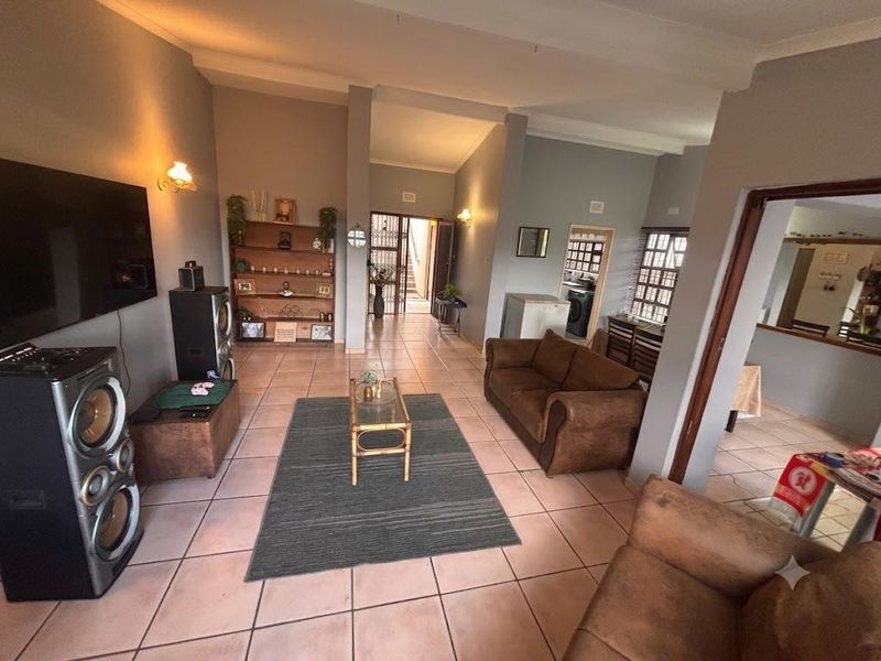 Spacious living area featuring tiled flooring and neutral wall tones, providing a functional layout with direct access to adjacent rooms.