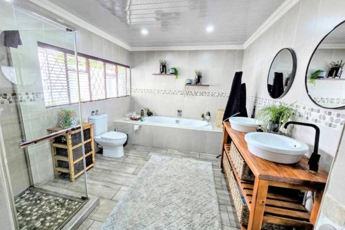 Modern bathroom featuring a glass-enclosed shower, built-in bathtub, dual vessel sinks, and contemporary tiled finishes throughout.
