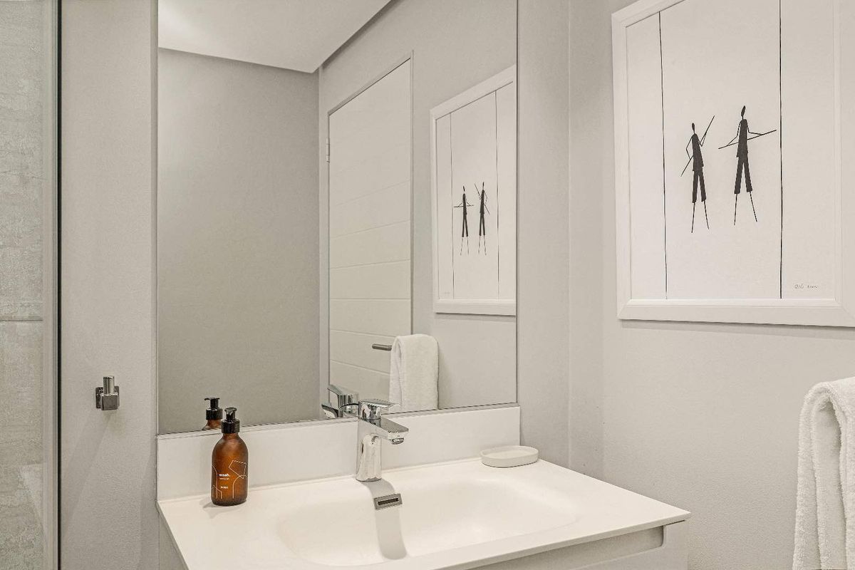 A modern, well-maintained bathroom featuring a clean vanity basin with a chrome mixer tap and a large wall-mounted mirror.