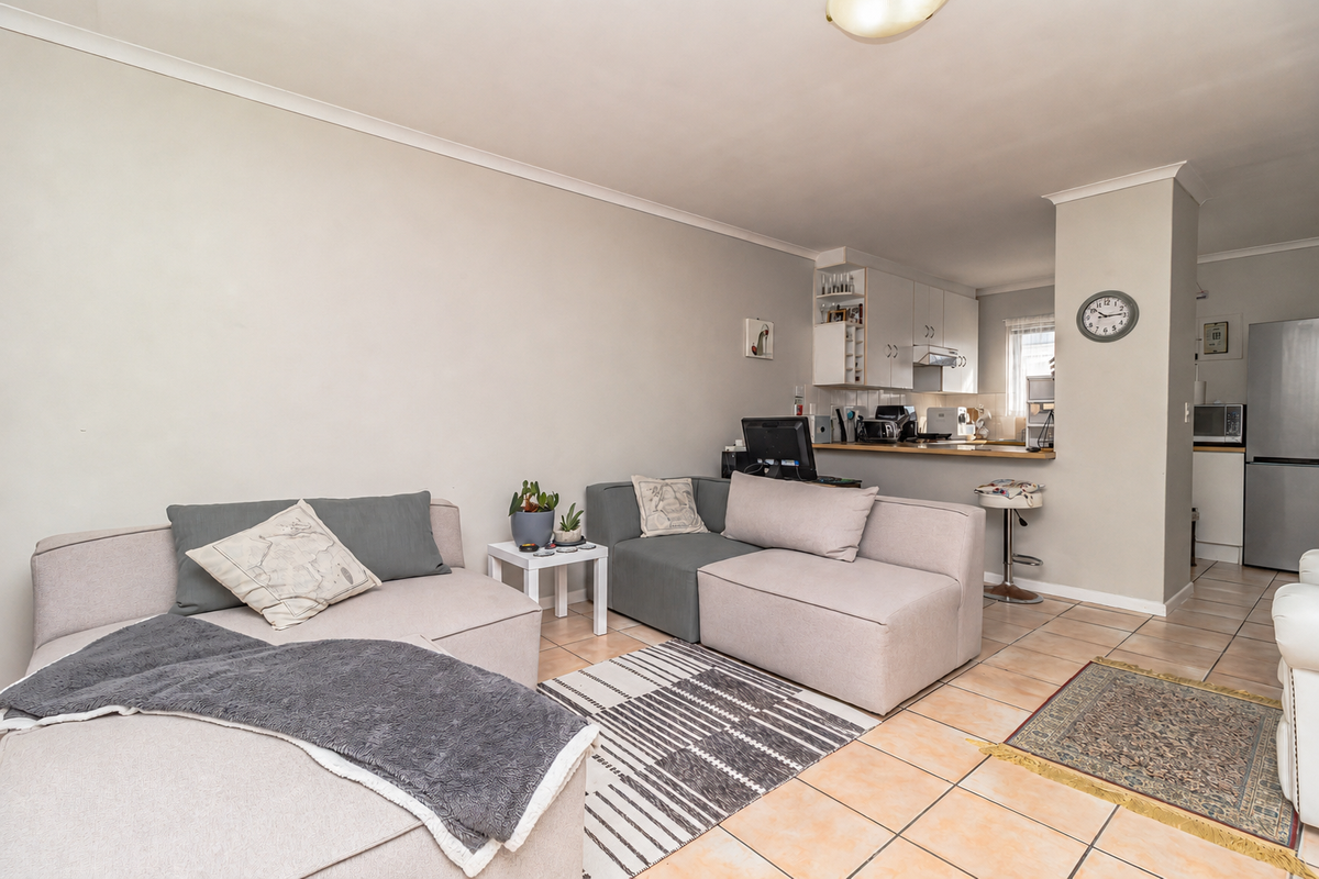 Open-plan living area featuring tiled flooring and a functional kitchen with built-in cabinetry and a breakfast counter.
