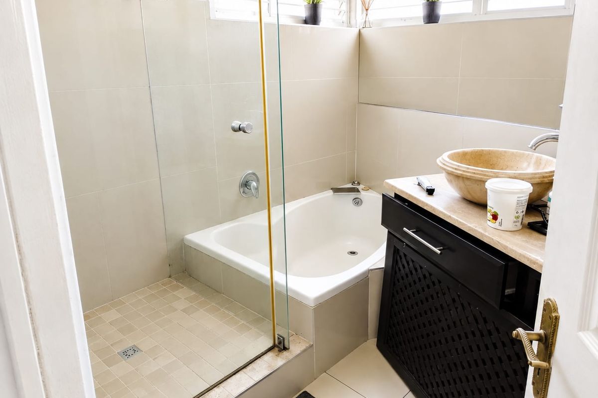 A functional bathroom featuring a built-in bathtub, glass-enclosed shower, and a stone-topped vanity with a vessel sink.