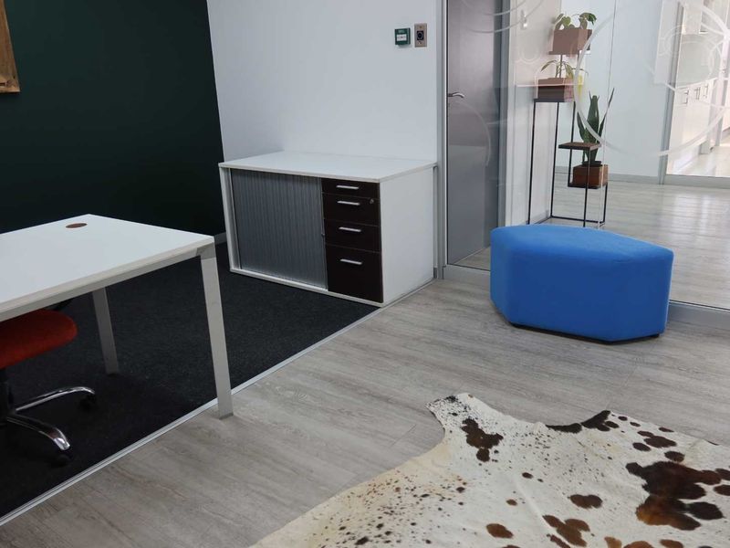 A modern office space featuring a mix of carpet and laminate flooring, separated by a glass partition wall.