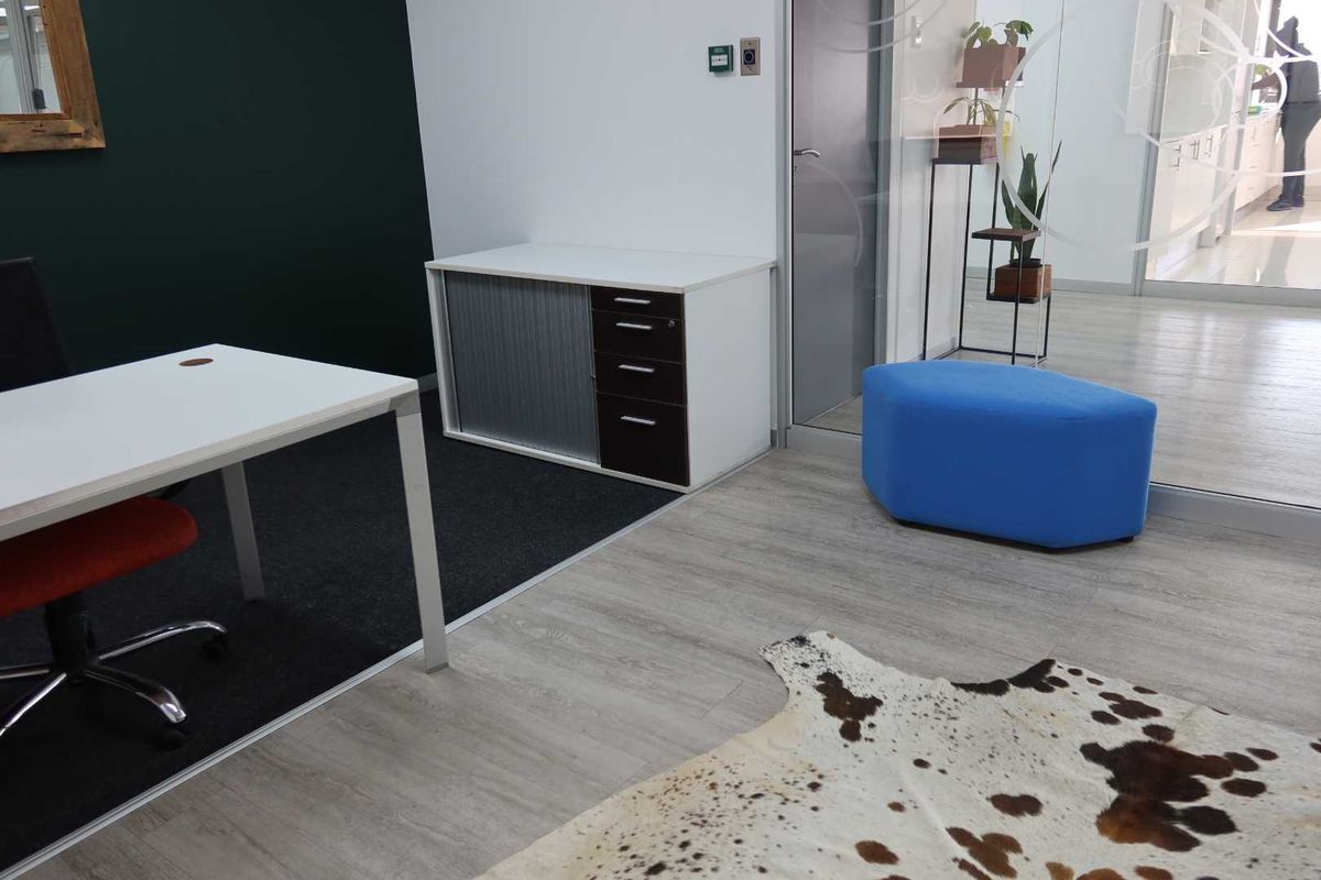 A modern office space featuring a mix of carpet and laminate flooring, separated by a glass partition wall.