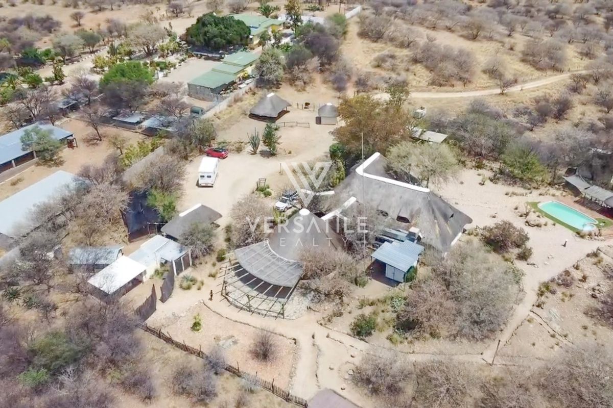 Aerial view of a small holding property featuring multiple outbuildings, a swimming pool, and extensive grounds in a rural landscape setting.