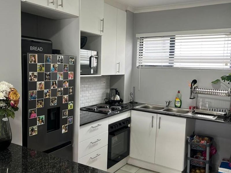A functional kitchen featuring white cabinetry, black granite countertops, a subway tile backsplash, and integrated cooking appliances.