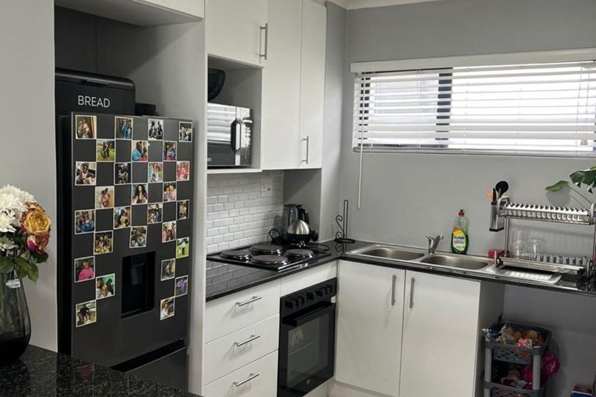 A functional kitchen featuring white cabinetry, black granite countertops, a subway tile backsplash, and integrated cooking appliances.