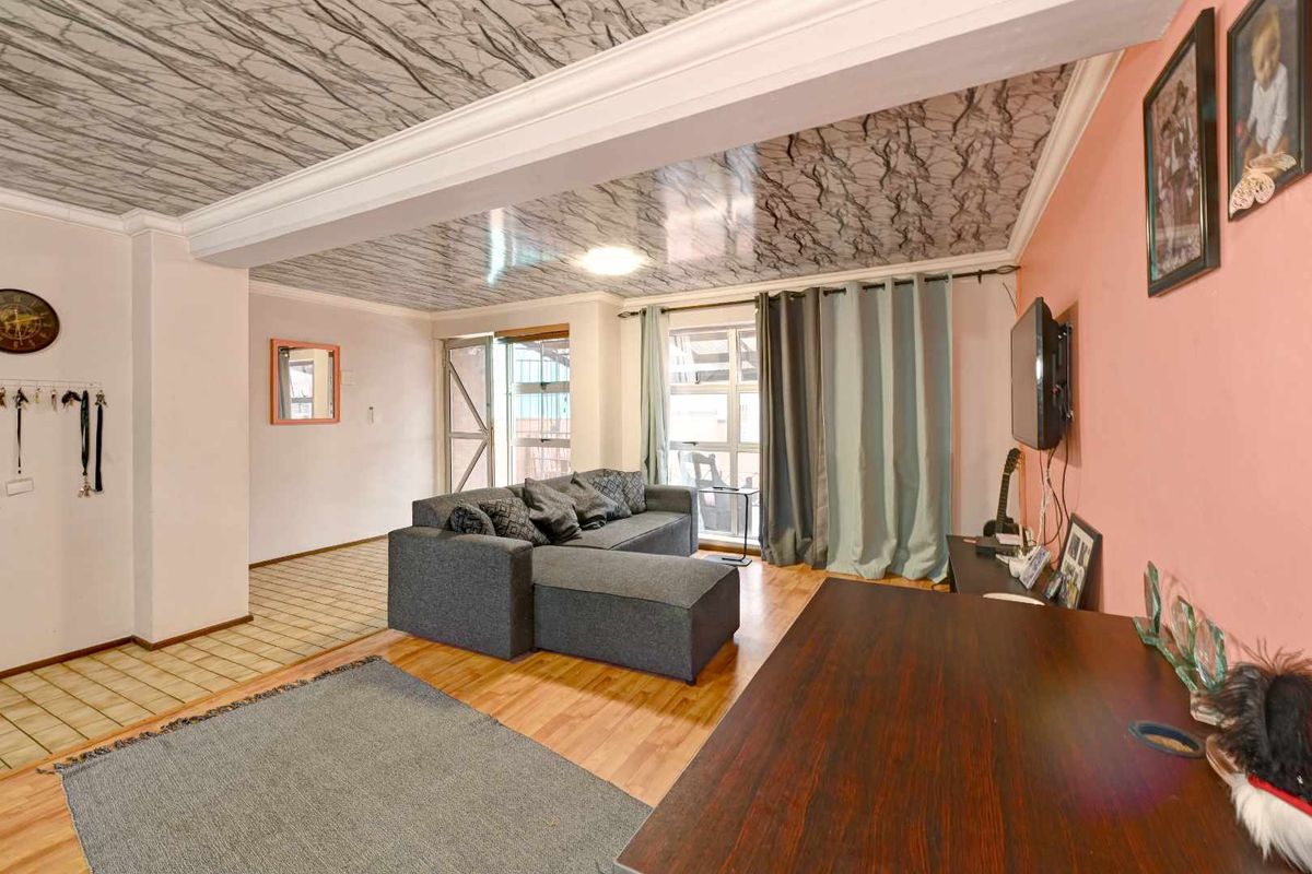 A living area featuring laminate flooring, a textured ceiling finish, and access to an outdoor balcony area.