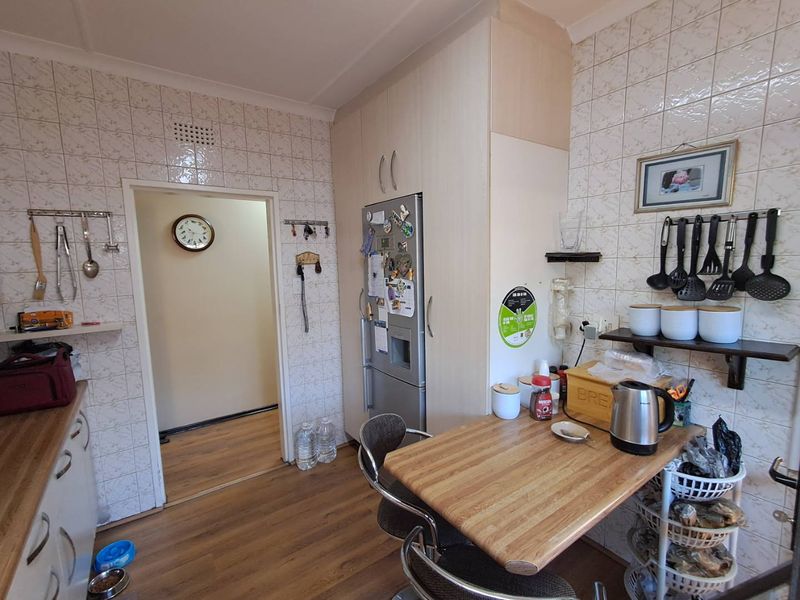 A functional kitchen featuring tiled wall finishes, built-in cabinetry, and laminate flooring, offering a practical layout for daily meal preparation.
