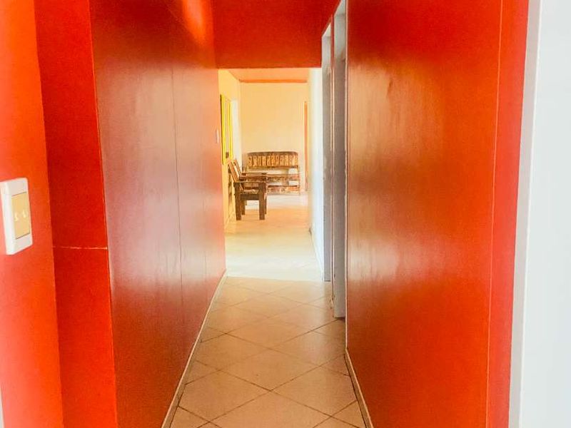 A bright hallway featuring tiled flooring and vibrant orange walls, providing access to adjacent rooms within the home.