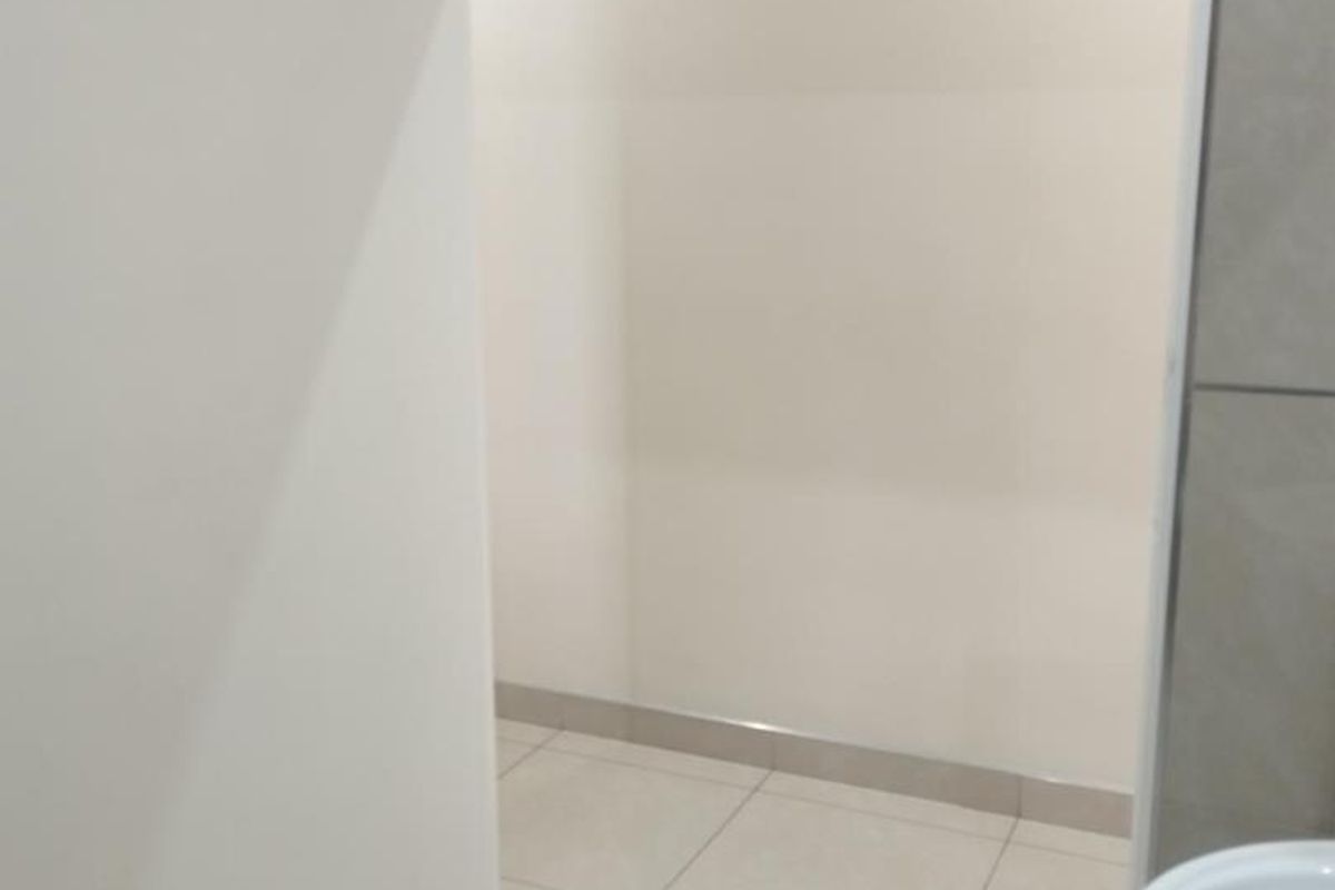 A clean, modern bathroom space featuring neutral floor and wall tiling, recessed lighting, and a minimalist washbasin.