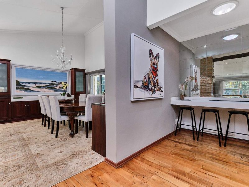 Open plan dining area featuring vaulted ceilings, hardwood flooring, and a built-in breakfast bar with a mirrored feature wall.