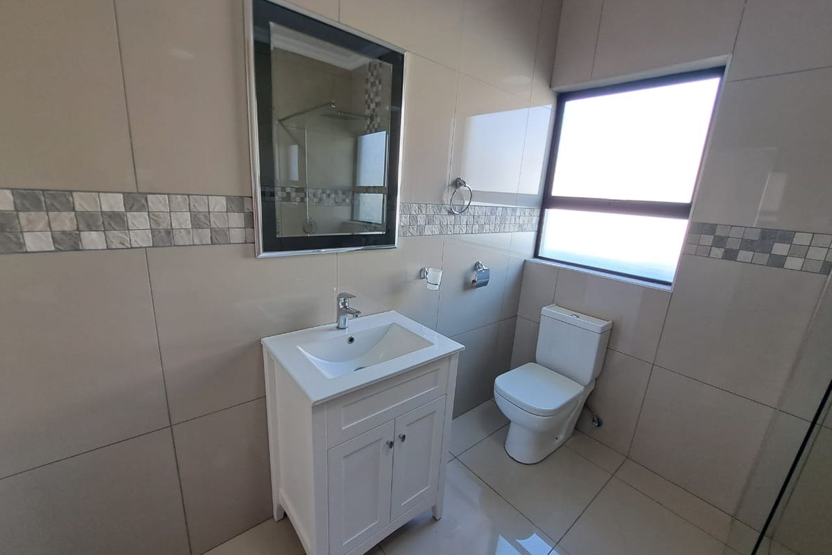 Modern bathroom featuring floor-to-ceiling neutral tiling, a contemporary vanity with basin, and a sleek toilet.